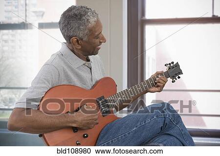 Stock Image - Mixed race man playing electric guitar. Fotosearch
