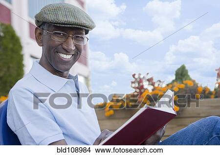 Mixed race man reading book outdoors View Large Photo Image Picture - Mixed race man reading book outdoors. Fotosearch