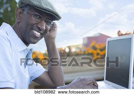 Mixed race man using laptop outdoors View Large Photo Image Stock Image - Mixed race man using laptop outdoors. Fotosearch