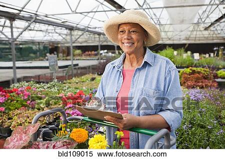 Stock Photography - Mixed race woman working in plant nursery. Fotosearch