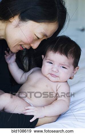 Mother holding baby on bed View Large Photo Image Stock Photo - Mother holding baby on bed. Fotosearch