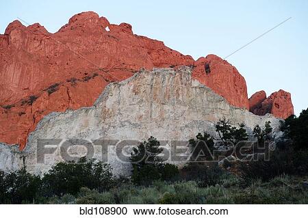 Stock Image - Red cliffs rising in rural landscape. Fotosearch
