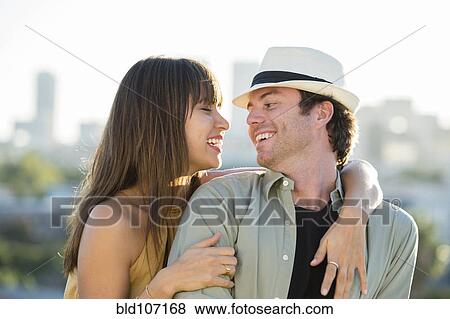 Smiling couple hugging on city street View Large Photo Image Stock Photo - Smiling couple hugging on city street. Fotosearch