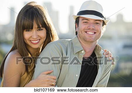 Stock Photo - Smiling couple hugging on city street. Fotosearch
