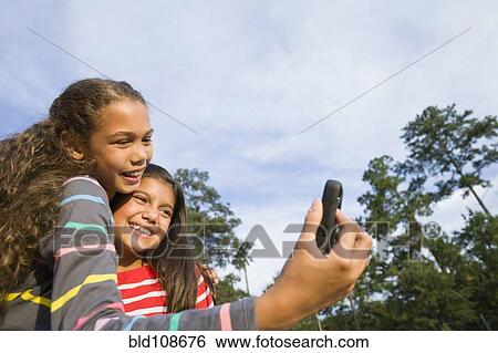 Stock Photograph - Smiling girls taking pictures outdoors. Fotosearch