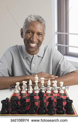 Picture - Smiling mixed race man playing chess. Fotosearch