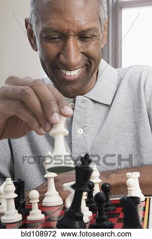Stock Image - Smiling mixed race man playing chess. Fotosearch