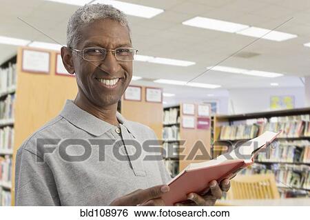 Stock Photograph - Smiling mixed race man reading in library. Fotosearch