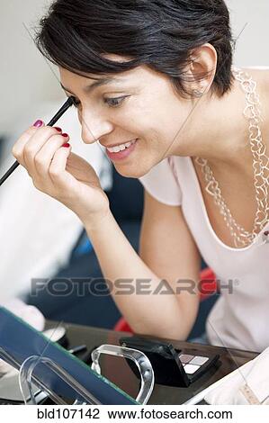 Stock Image - Smiling woman applying make up. Fotosearch