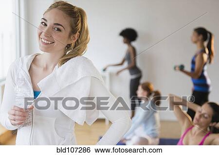 Stock Photograph - Smiling woman drinking water in gym. Fotosearch