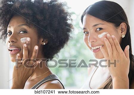 Smiling women applying moisturizer to cheeks View Large Photo Image Stock Image - Smiling women applying moisturizer to cheeks. Fotosearch