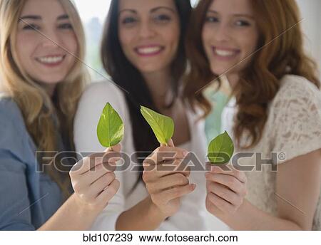 Stock Photo - Smiling women holding green leaves. Fotosearch