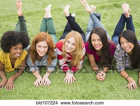 Smiling women laying in grass together View Large Photo Image Picture - Smiling women laying in grass together. Fotosearch