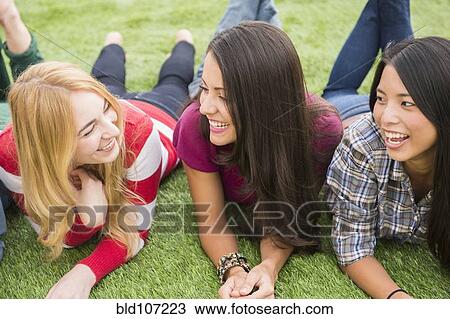 Smiling women laying in grass together View Large Photo Image Stock Image - Smiling women laying in grass together. Fotosearch