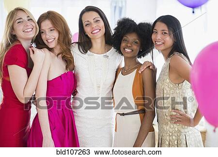 Stock Image - Smiling women standing together at party. Fotosearch