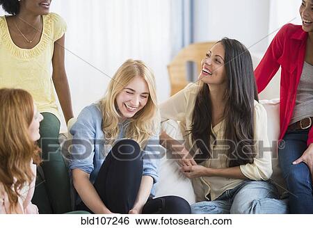 Stock Photograph - Smiling women talking on sofa. Fotosearch