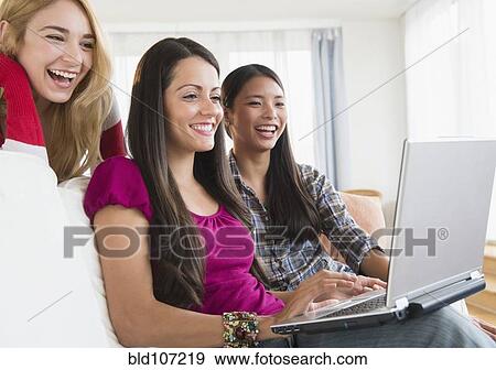 Smiling women using laptop together View Large Photo Image Stock Photo - Smiling women using laptop together. Fotosearch