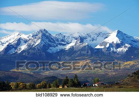 Snowy mountains overlooking rural landscape View Large Photo Image Stock Photo - Snowy mountains overlooking rural landscape. Fotosearch