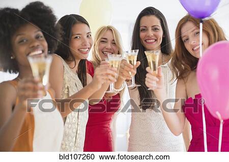 Women toasting each other with champagne at party View Large Photo Image Stock Image - Women toasting each other with champagne at party. Fotosearch