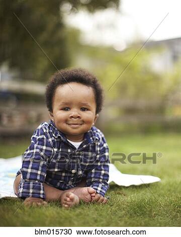 Stock Image - African American baby sitting in grass. Fotosearch