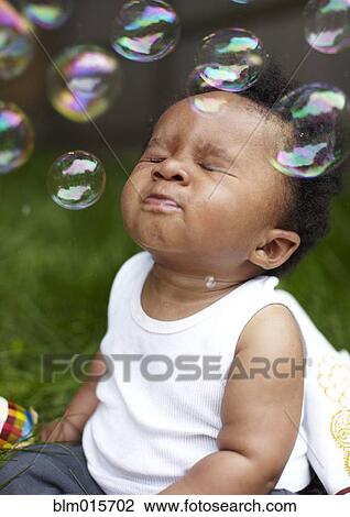 Stock Image - African American boy playing with bubbles. Fotosearch
