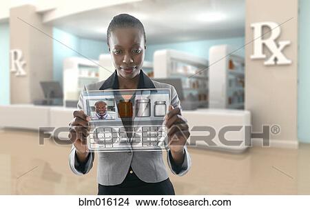 Picture - African American businesswoman using digital display in pharmacy. Fotosearch