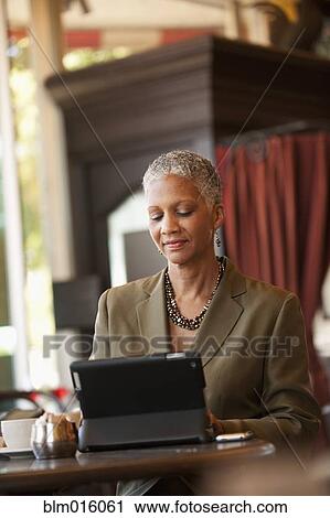 Stock Image - African American businesswoman using digital tablet in cafe. Fotosearch