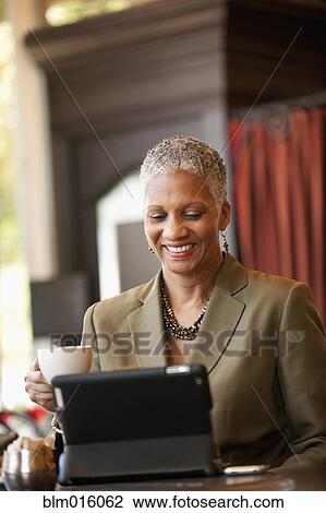 Stock Image - African American businesswoman using digital tablet in cafe. Fotosearch