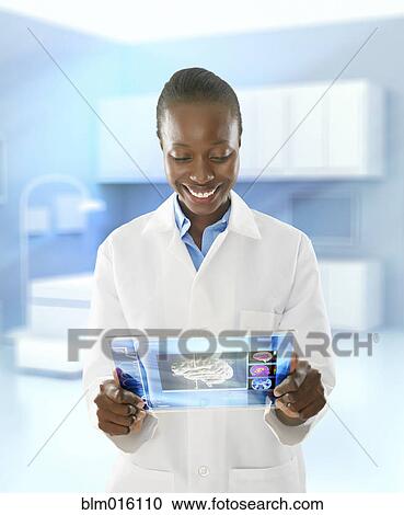 Stock Image - African American doctor using digital tablet in doctor's office. Fotosearch