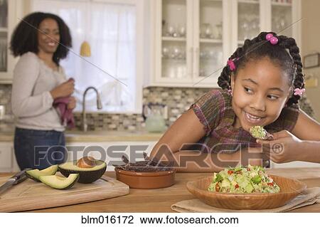 Stock Image - African American mother and daughter making guacamole. Fotosearch