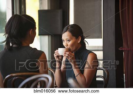 Stock Photograph - Asian friends sitting together in cafe. Fotosearch