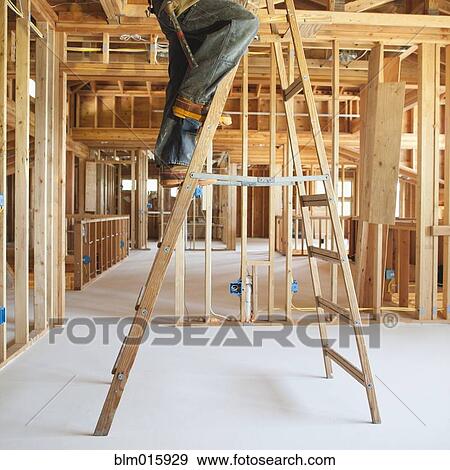 Stock Photo - Black carpenter working on ceiling of unfinished room. Fotosearch
