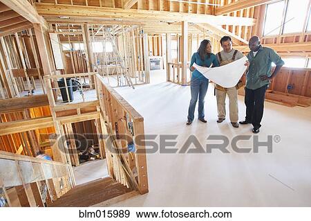 Stock Photo - Black couple and construction worker looking at blueprints in unfinished room. Fotosearch