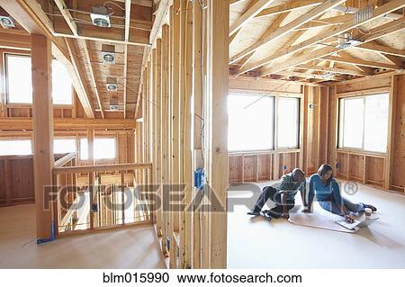 Stock Image - Black couple looking at laptop in unfinished room. Fotosearch