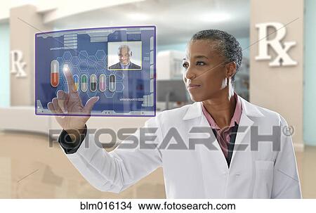 Picture - Black doctor using digital display in pharmacy. Fotosearch