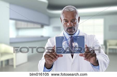Stock Photography - Black doctor using digital display in doctor's office. Fotosearch