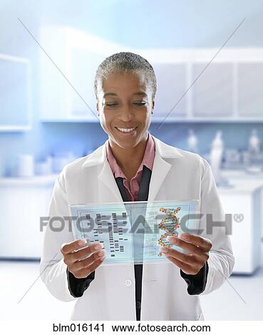 Stock Image - Black doctor using digital tablet in doctor's office. Fotosearch
