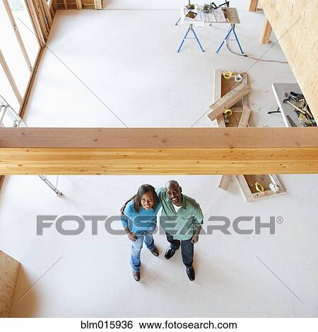 Stock Photograph - Black home owners standing in unfinished room. Fotosearch