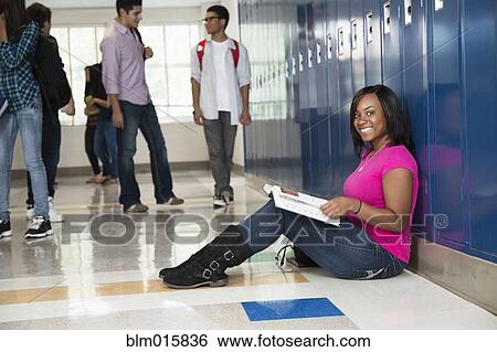 Stock Photograph - Black student sitting in high school corridor. Fotosearch