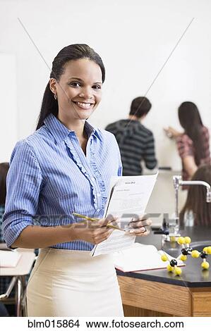 Black teacher holding paperwork in classroom View Large Photo Image Picture - Black teacher holding paperwork in classroom. Fotosearch