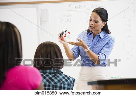 Stock Image - Black teacher showing students chemistry model. Fotosearch