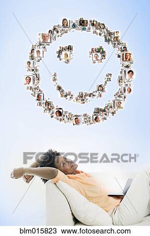 Stock Image - Black woman looking at smiley face made up of pictures. Fotosearch