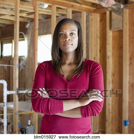 Stock Photo - Black woman standing in unfinished room. Fotosearch