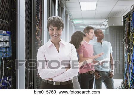Stock Image - Business people standing in server room. Fotosearch