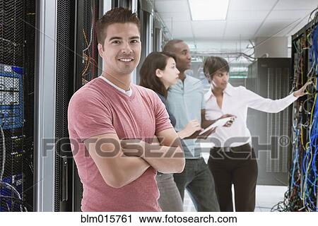 Stock Image - Business people standing in server room. Fotosearch
