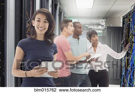 Stock Image - Business people standing in server room. Fotosearch