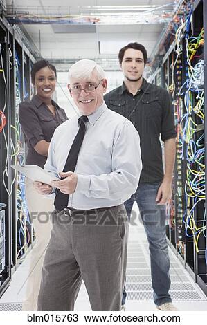 Stock Image - Business people standing in server room. Fotosearch