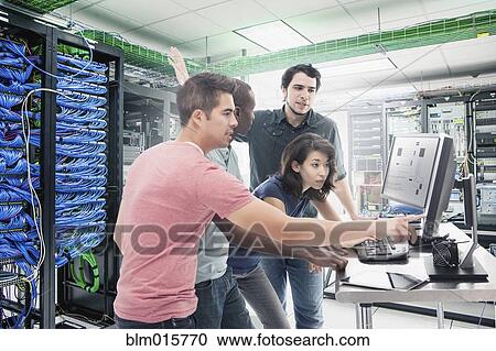 Stock Image - Business people working in server room. Fotosearch