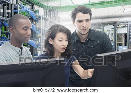 Stock Image - Business people working in server room. Fotosearch