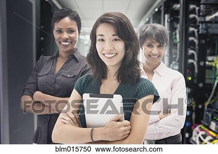 Stock Image - Businesswomen standing in server room. Fotosearch